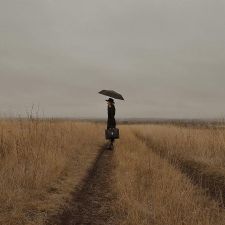 Eine Frau steht auf einem abgeernteten Feld mit einem Schirm in der Hand